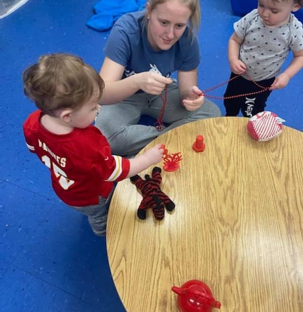 Educator with children at Mini Adventures Preschool in Warrensburg, MO engaging in a playful learning activity.