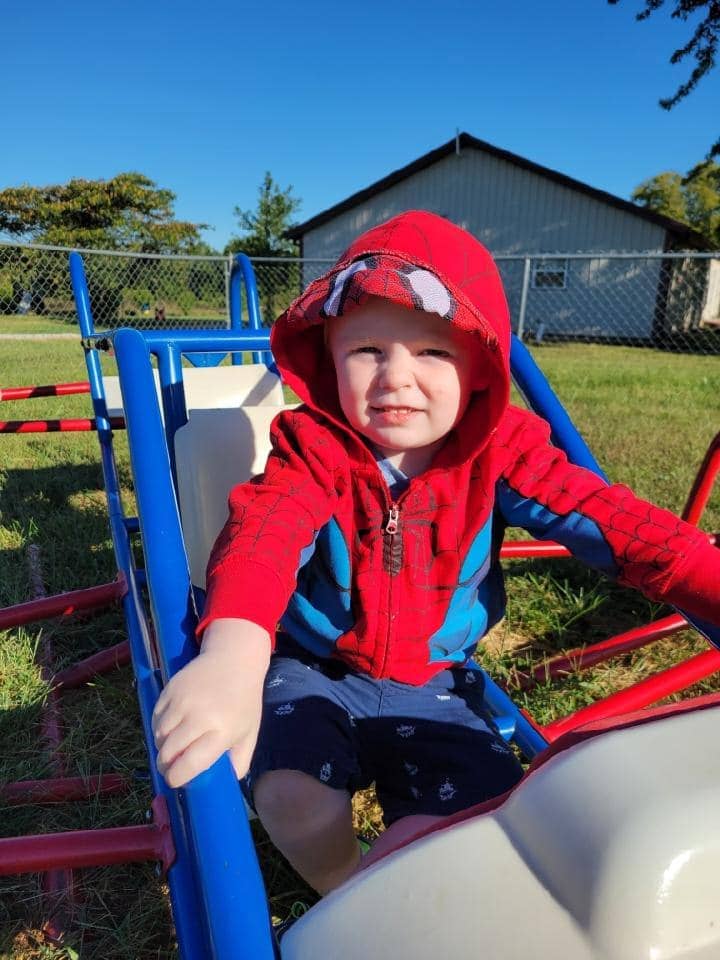 Child enjoying a playful moment at Mini Adventures Preschool in Warrensburg, surrounded by outdoor play equipment.