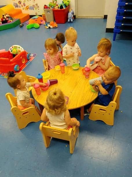 Toddlers engaging in play-based learning at a daycare in Warrensburg, MO, seated around a table with activities.