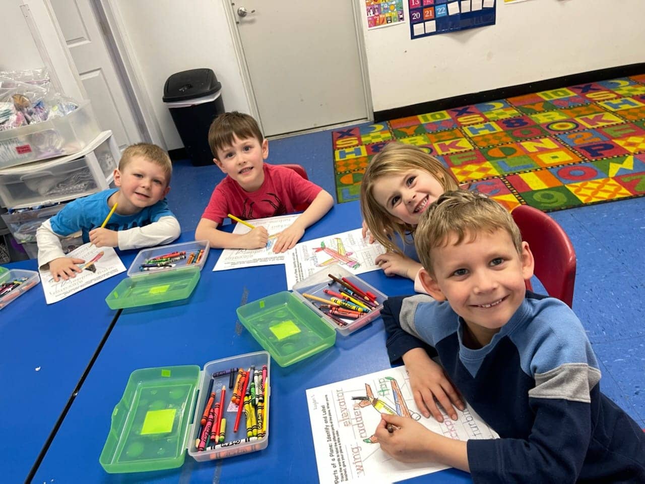 Preschool children in Warrensburg, MO engaging in play-based learning with coloring activities at a table.