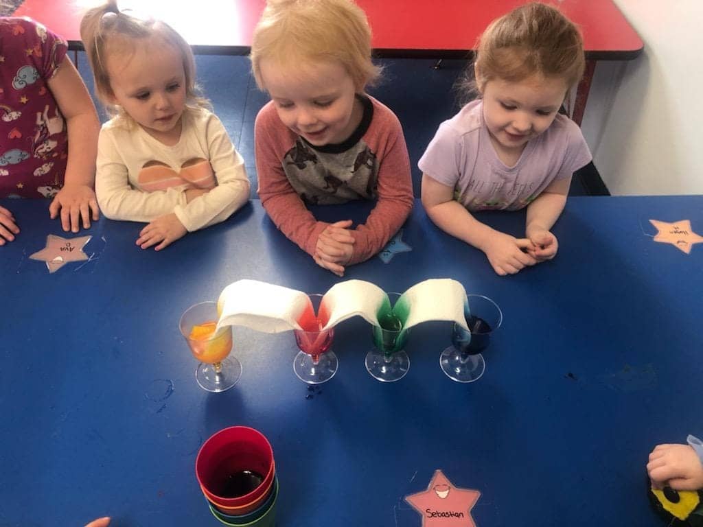 Preschool children in Warrensburg, MO engaged in a play-based learning activity with colored liquids.