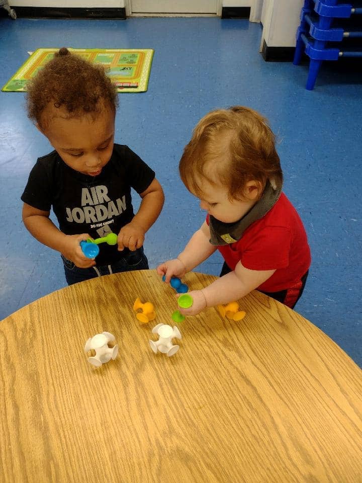 Two toddlers engaging in play-based learning activities at a daycare in Warrensburg, MO.